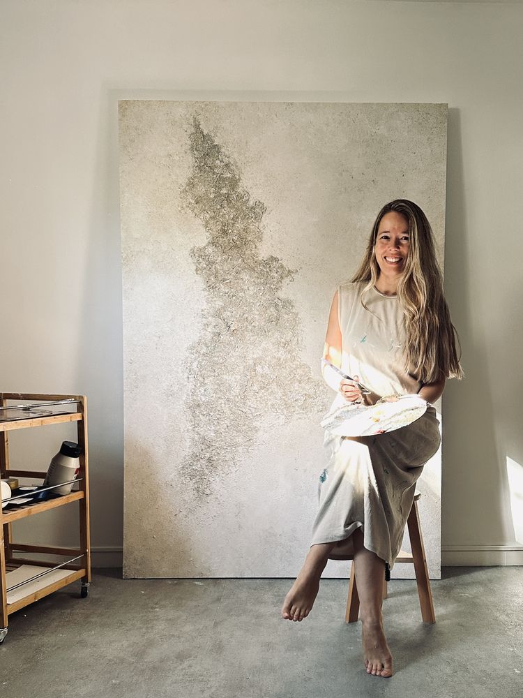 Tania en su estudio junto a una obra en tonos dorados